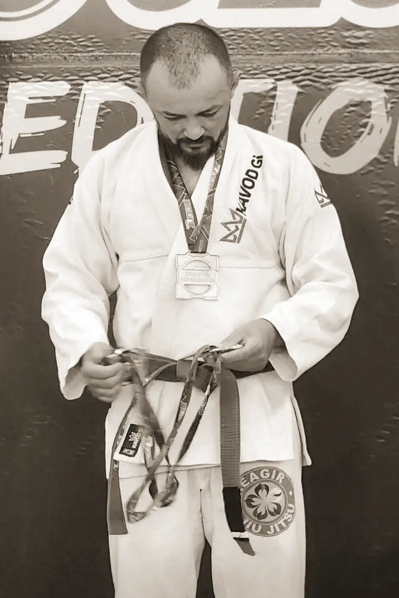 Pécora de kimono branco olhando as medalhas nas mãos, na premiação